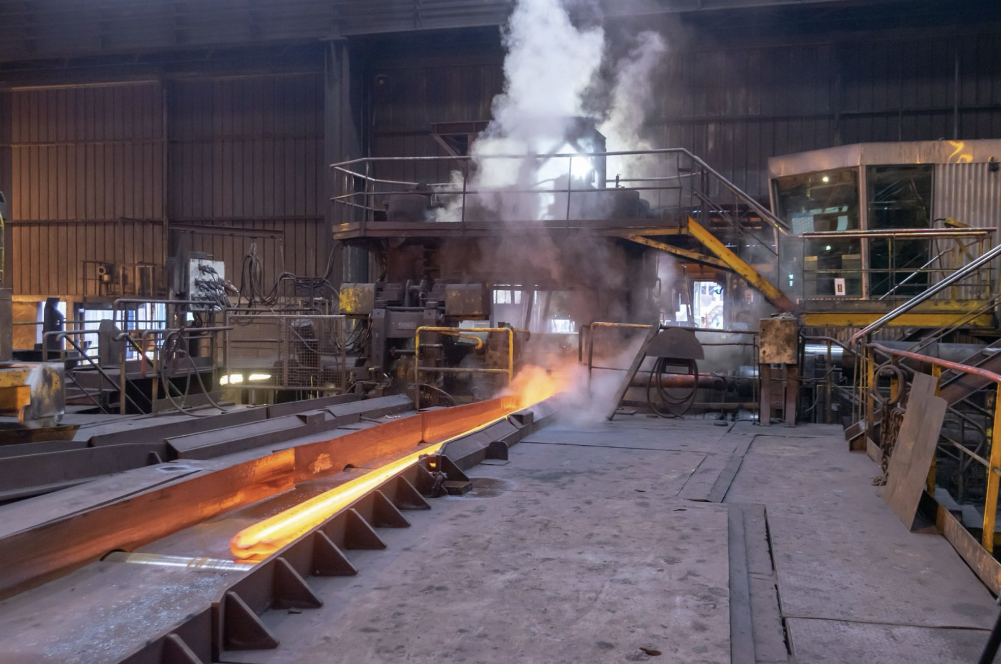 Hot rolled steel bar moving across a foundry mill floor